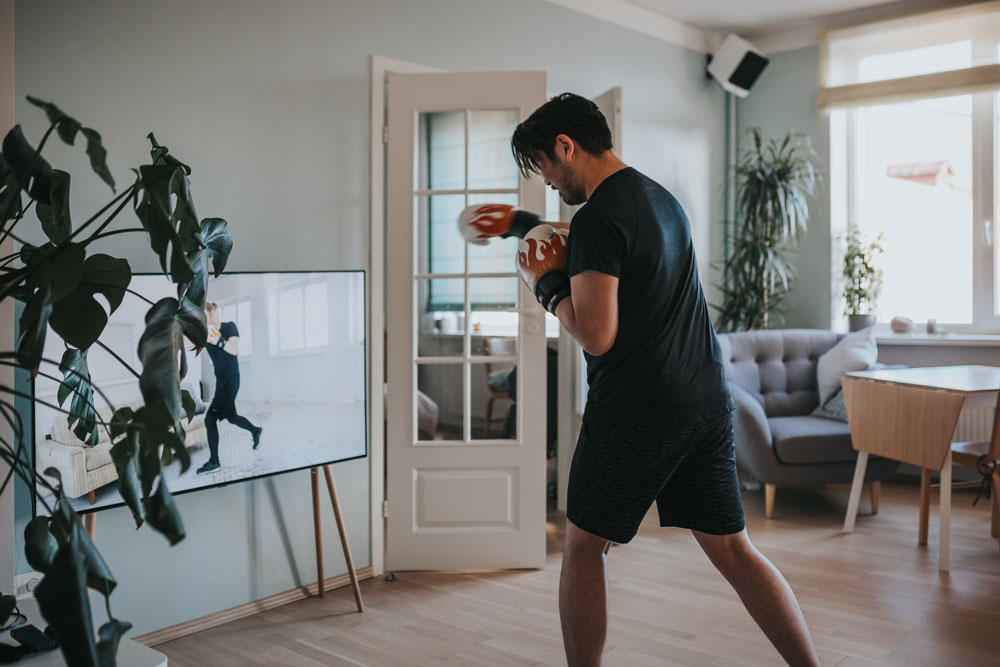 En man som tränar boxning hemma framför en TV.